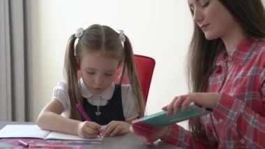 Mom teaching her daughter to read and write at home