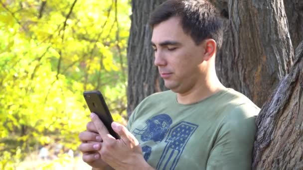 Man Smartphone Stands Autumn Park — Vídeo de stock