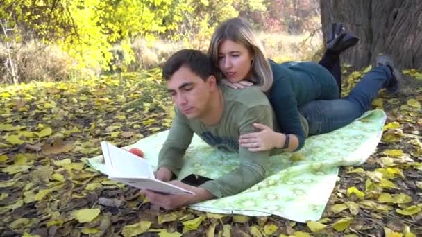 美しい秋の公園で座って 本を読んで幸せなカップル — ストック動画