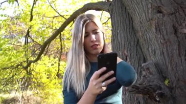 mutlu genç kadın cep telefonuyla sonbahar park
