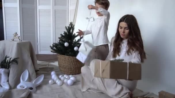 年轻的母亲和她的儿子在圣诞树前打开了一个圣诞礼品盒 — 图库视频影像