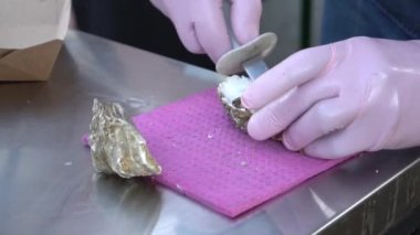 Someone shucking an oyster as water drips out of it.