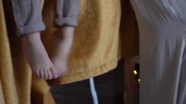 Küçük bir bebek yüksek sandalye yemek masasında otururken ayaklar