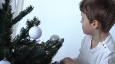 Slow Motion. Evde Noel ağacı süsleyen sevimli küçük çocuk.