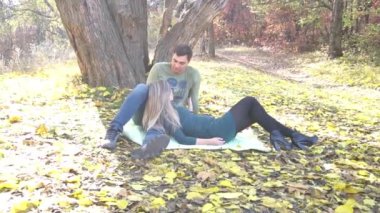 Beautiful young couple in love in autumn sitting under a tree in the park 