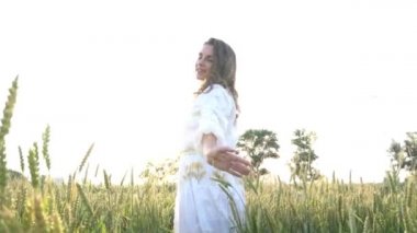 Slow Motion girl in an embroidered shirt at sunset in a wheat field