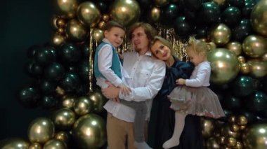 Slow Motion dad and mom with a kids stands on a photo zone with balloons 