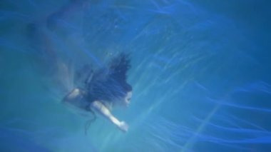 Slow Motion model in water in a beautiful dress swims