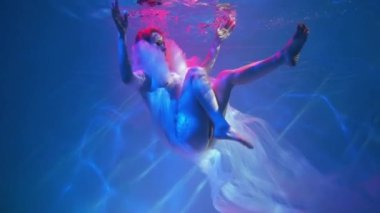 Slow Motion Güzel kadın zarif elbisesiyle suyun altında yüzüyor