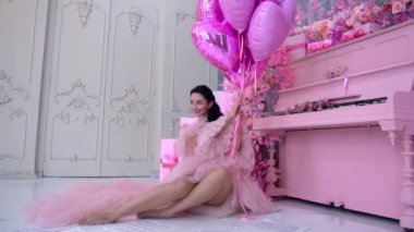 Piyanonun yanındaki pembe elbiseli güzel genç bayan.