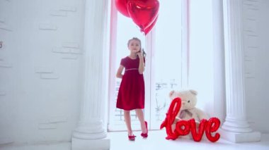 sevimli küçük kız elinde bir demet kırmızı kalpli balon