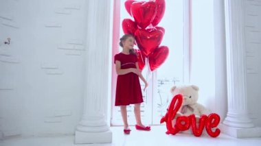 Slow Motion girl in a red dress with red gel balloons and white toy teddy bear 