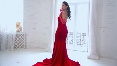 Slow Motion tractive woman in red dress in the spacey room near the window.