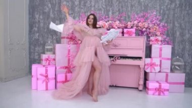 Beautiful pregnant female in a pink dress on a background of bright interior
