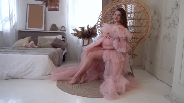 Urocza Ciężarna Kobieta Różowej Sukience Siedzi Miękkim Krześle Pokoju — Wideo stockowe