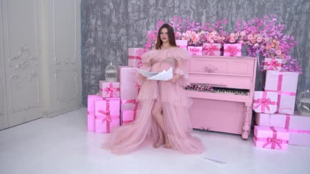 Slow Motion Elegante Zwangere Vrouw Een Roze Jurk Bij Piano — Stockvideo