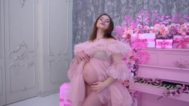 Slow Motion Elegante Zwangere Vrouw Een Roze Jurk Bij Piano — Stockvideo