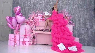 Beautiful elegant girl in a long red dress drop notes next to the piano