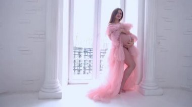 Slow Motion Beautiful pregnant young woman is wearing luxury pink dress