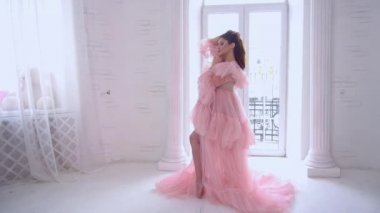 Slow Motion Fashion pregnant woman is wearing luxury pink dress, studio