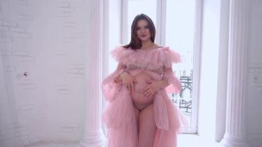 Slow Motion Young pregnant woman at home touching her belly tenderness