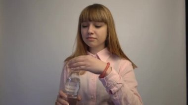 4k Young girl drinking water from bottle isolated on a gray background