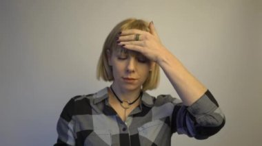 4k A young attractive woman suffering from illness or headache holding her head