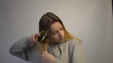 4k Girl combing hair. Beautiful young woman holding comb straightened hair. 