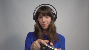 4k Teen girl in headphones plays video games with a gamepad in her hands. Gamer 