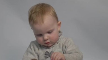 Baby girl wiping nose with white paper towel on light gray background