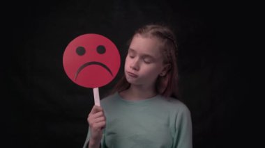 4k close-up portrait of lonely little child holding sad face symbol
