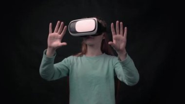 4k girl wearing virtual reality goggles standing on black background.