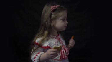 4k Cute baby girl eating cookies on black background