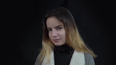 4k A curious girl stands against the black background and thinks