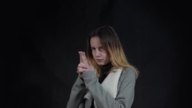 4k Young brunette teenager holding symbolic gun, playing  with hand gesture 