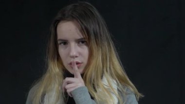 Slow Motion young caucasian girl makes silence gesture, keeps finger over lips