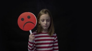 4k Little girl holding happy and sad face masks symbolizing changing emotions