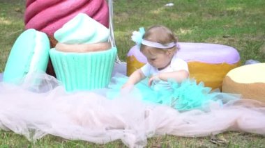 portrait of cute little girl with huge macaroons, donuts and cupcakes decoration