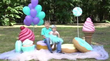 Brother and sister near big fake candies. Photo zone in the garden.