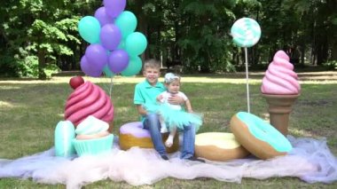 Slow Motion cute little girl and boy with big cake and lollipops on nature