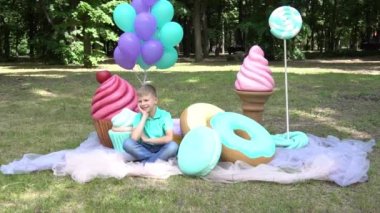 Slow Motion Boy resting on sofa in park on background of large lollipops