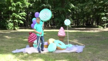 Slow Motion Boy resting on sofa in park on background of large lollipops