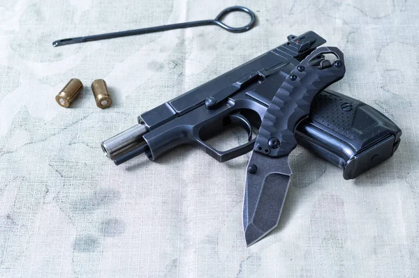 Складной карманный нож и пистолет. Травматический пистолет и пули. Чистящий стержень для чистки пистолета. — стоковое фото