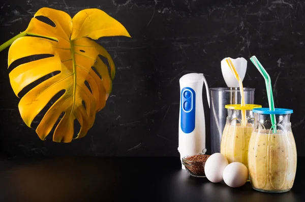 Elektrikli blender ve kokteyl. Tavuk yumurtası ve bardakta kokteyl. Kokteyl yapıyorum. Siyah arkaplan.