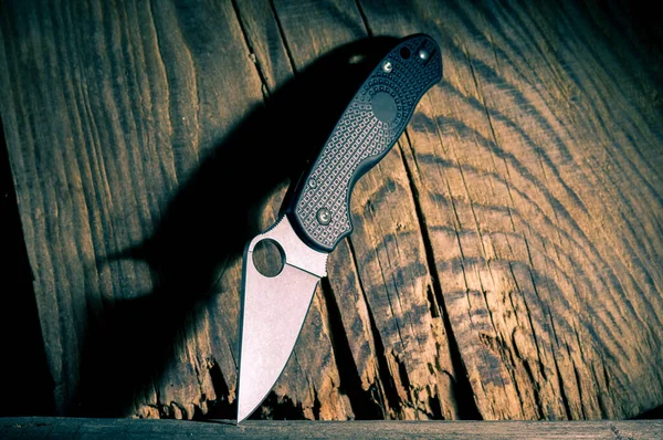 Bıçakta bir delik var. Bıçak ve sert bir gölge. Ahşap bir arka planda bıçak. Çapraz bıçak.