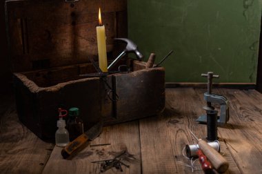 Aletleri olan bir işyeri. Eşyalar ve aletler masada. Yine de aletlerle dolu bir hayat. Mum ışığında çalış. Mum ve el aletleri. Alçak tuş ön görünümü.