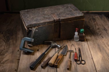 Masada bir takım eski aletler var. Masanın üzerinde çeşitli el aletleri var. Klasik ve sade. Ön görünüm.