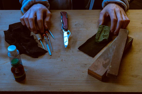 Modern mes en oude slijpstenen. Moderne en vintage instrumenten. Handen op tafel en gereedschap. — Stockfoto