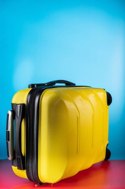 Sarı renkli bavulu çevir. Mavi arka planda sarı seyahat valizi.