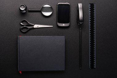 Siyah bir masada siyah renkli kırtasiye malzemesi. Düzgün katlanmış eşyalar. Flar yatıyordu. Yukarıdan görüntüle.